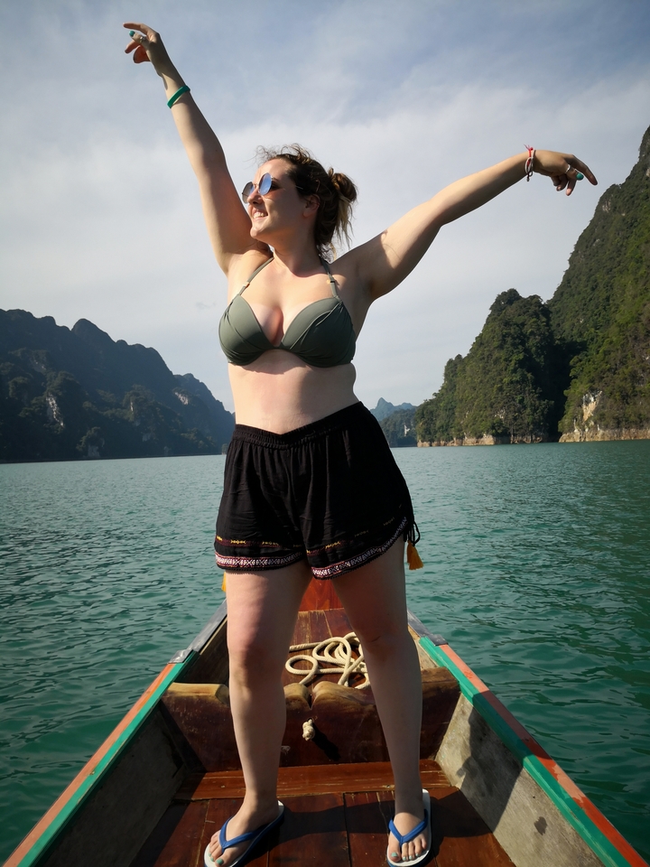 Person with cupped hands in a scenic landscape with water and hills.