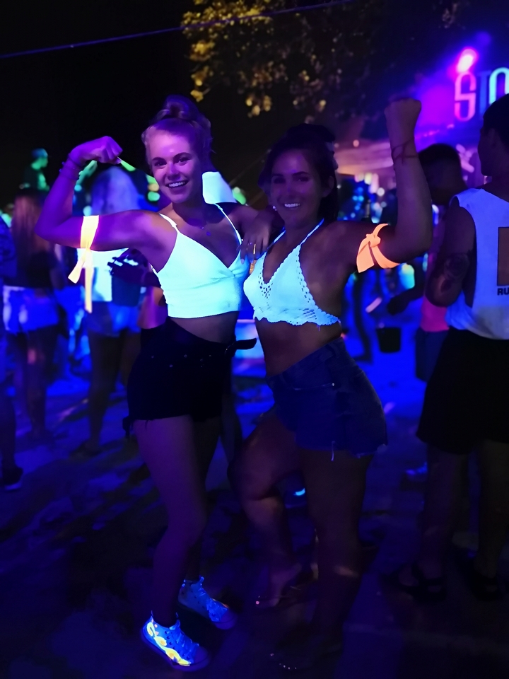 Twee vrouwen poseren op een neonfeest.