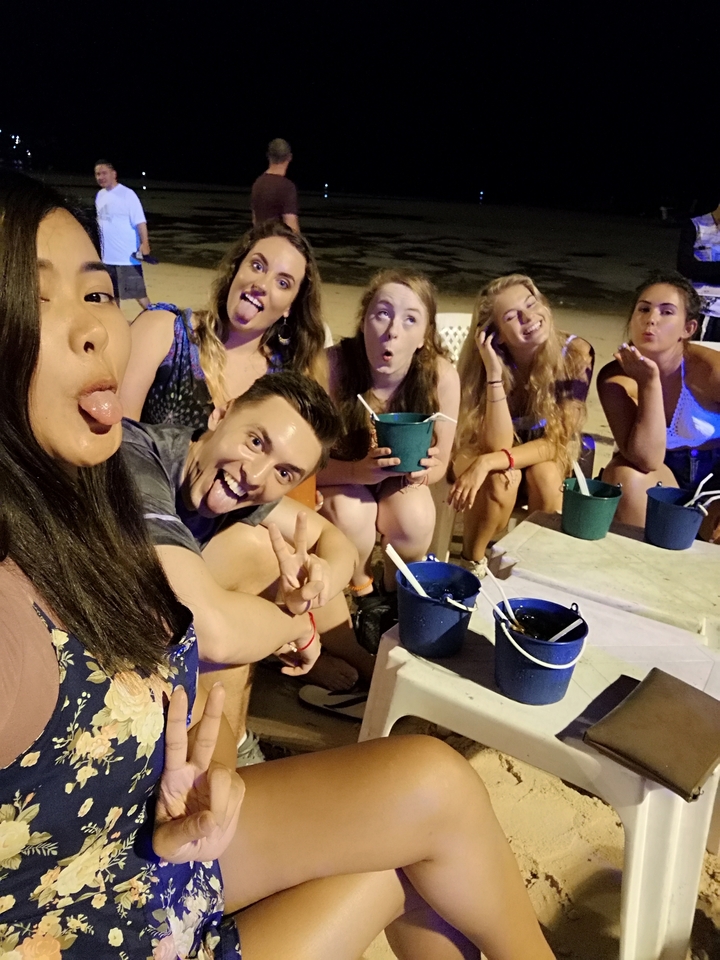 Vrienden die grappige gezichten en gebaren maken bij een strandvuur.