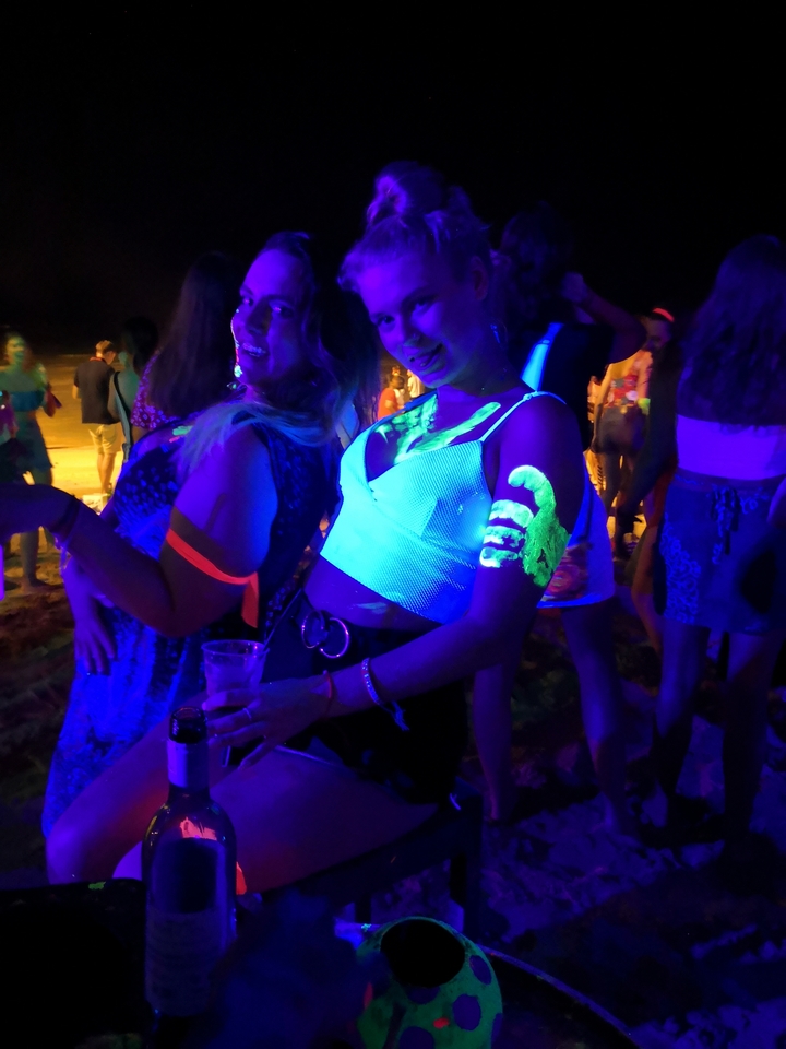 Zwei Frauen mit Leuchtfarbe genießen eine Strandparty.