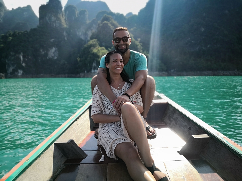 Couple sitting happily at the front of a boat in turquoise waters.