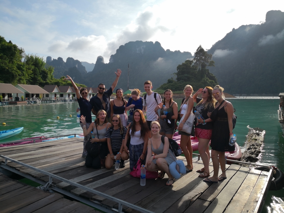 Group of people posing on a dock with mountains behind them.