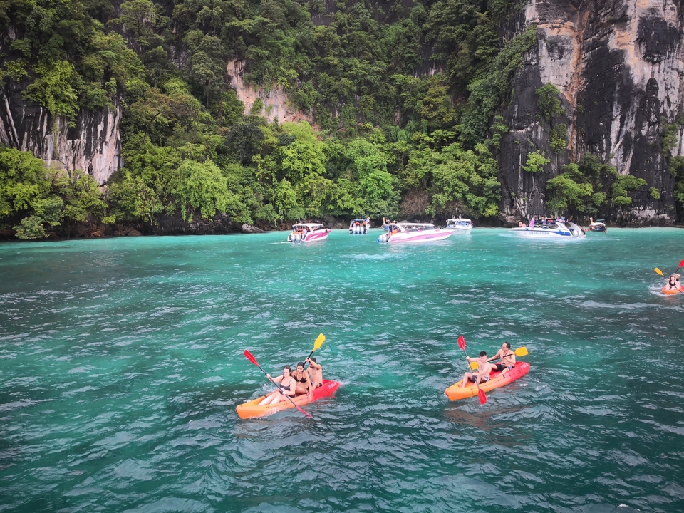 People kayaking with cliffs in the background.