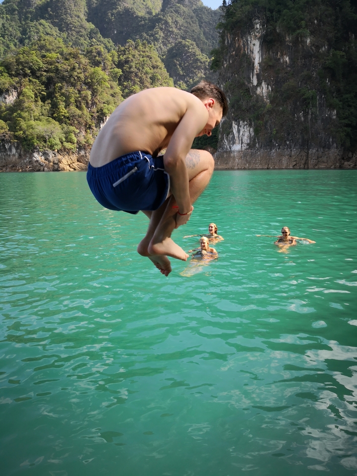 Person jumping into the water with others swimming.