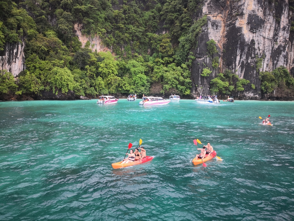 People kayaking and boats in a turquoise bay.