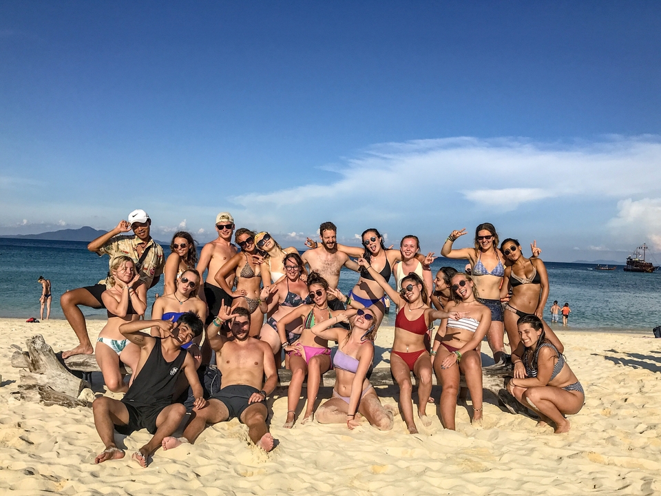 Group of people posing on a beach.