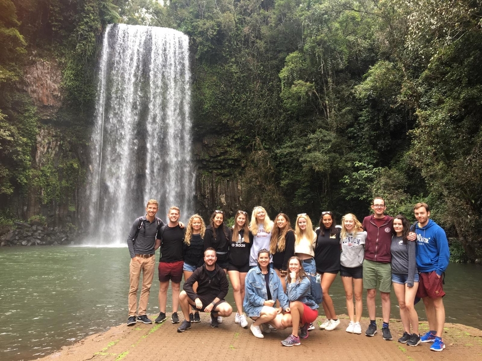 Grand groupe posant devant une cascade.