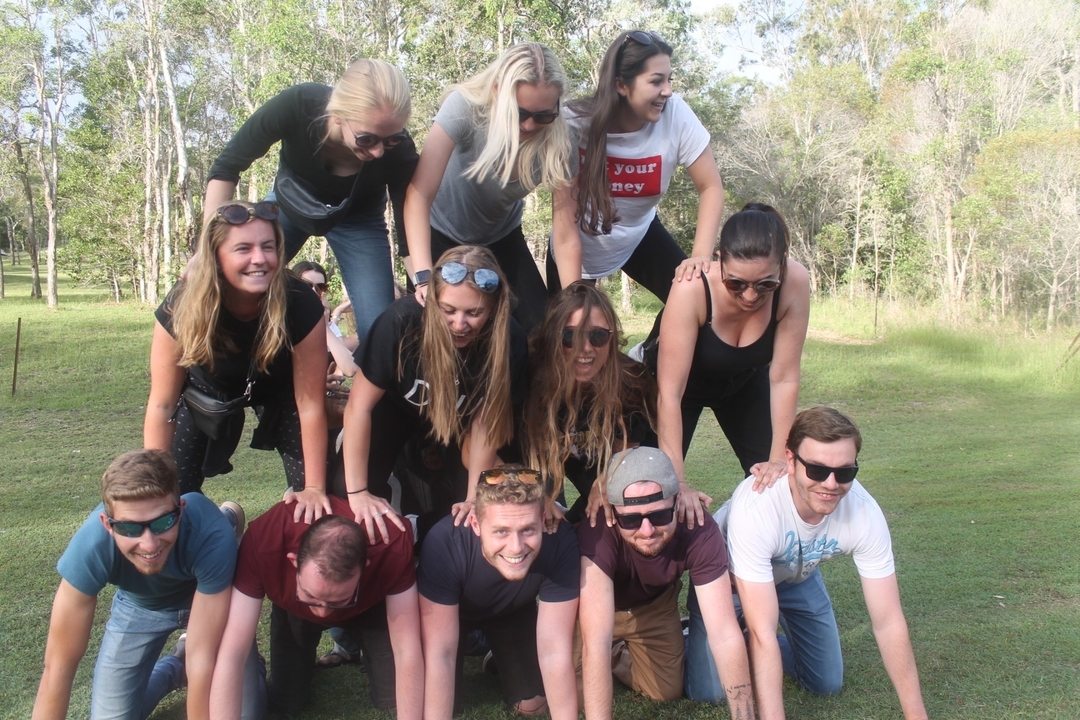 Groupe de personnes formant une pyramide humaine dans une zone herbeuse.