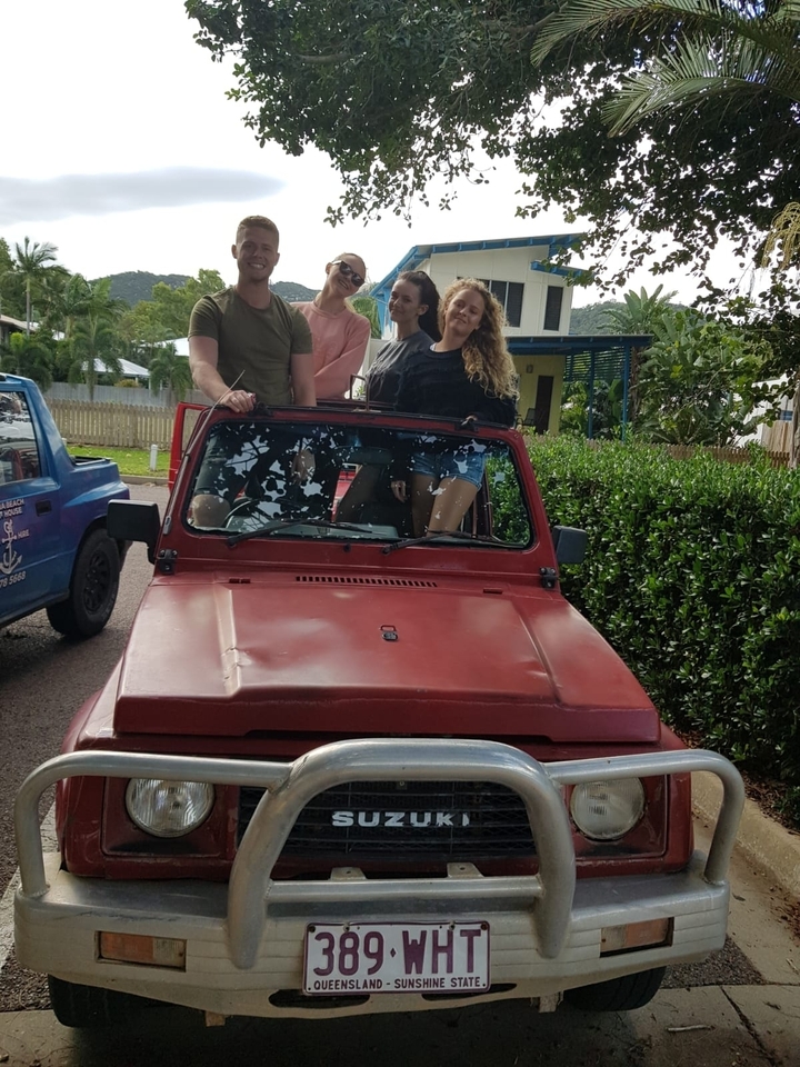 Groupe de personnes debout sur une jeep rouge.