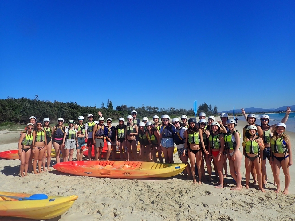 Un grand groupe de personnes avec des kayaks sur la plage.