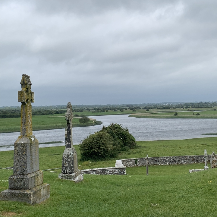Croix de pierre dans un paysage verdoyant avec une rivière.