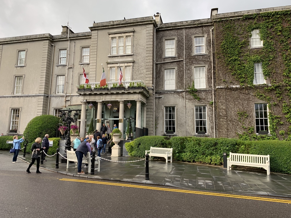 Groupe de personnes près d'un vieux bâtiment couvert de lierre.