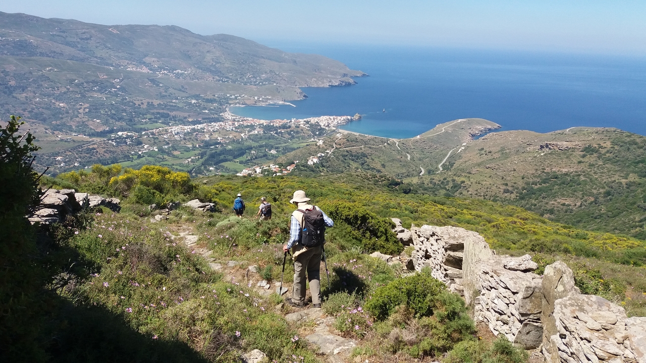 Randonneurs surplombant une ville côtière et la mer.