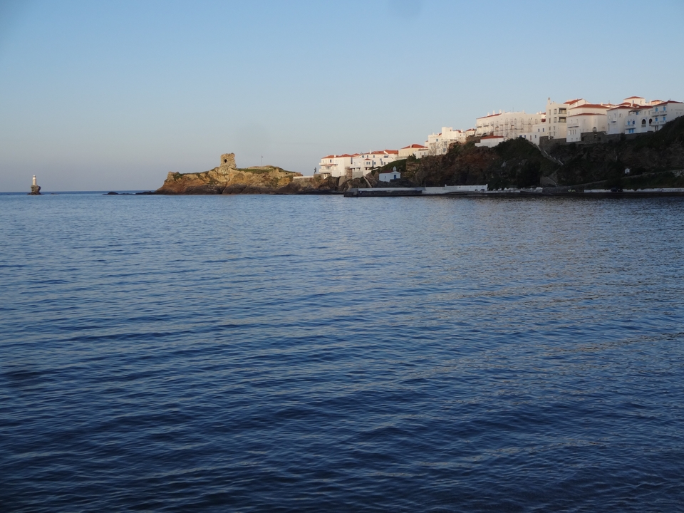 Vue côtière avec un phare et des bâtiments au bord de la mer.