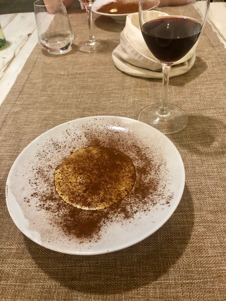 Dessert avec un saupoudrage de cacao et un verre en arrière-plan.