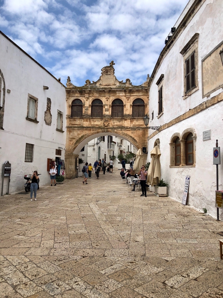 Des gens qui marchent dans une rue historique avec des cafés.