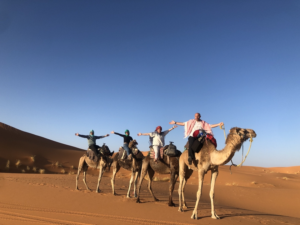 Groupe de personnes montant des chameaux dans le désert au coucher du soleil.