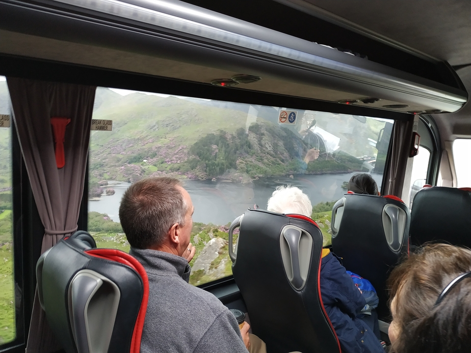 Vue depuis la fenêtre d'un bus, donnant sur un lac et des montagnes.