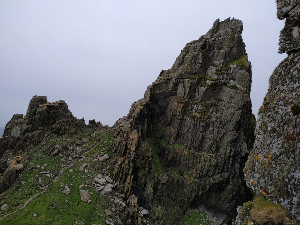 Falaise rocheuse escarpée sous un ciel nuageux.