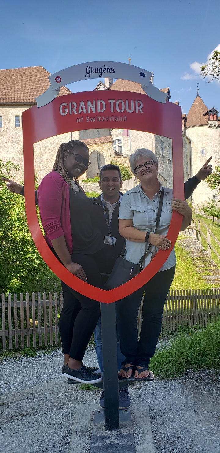 Trois personnes posant dans un grand cadre rouge à l'extérieur.