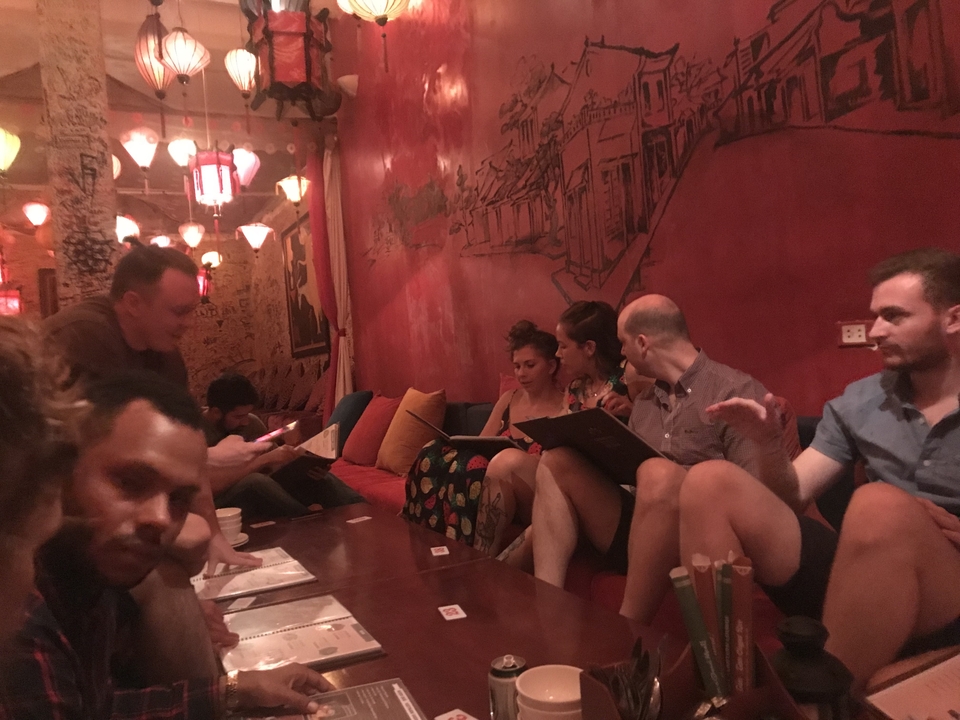 Groupe de personnes assises dans un café ou restaurant faiblement éclairé.