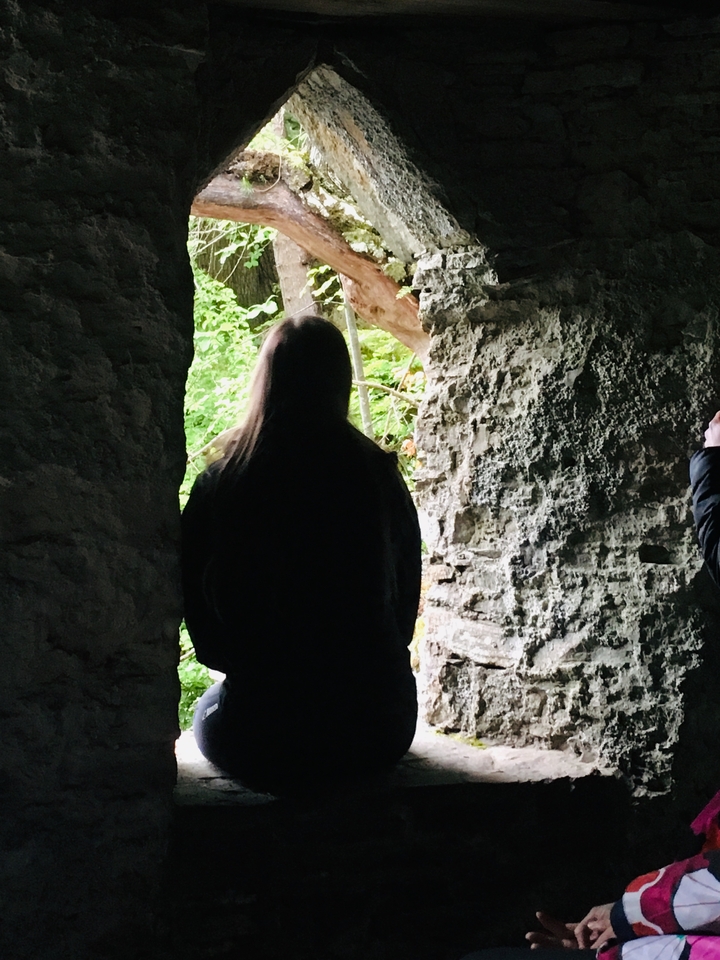 Personne debout dans une ruine regardant vers la forêt.