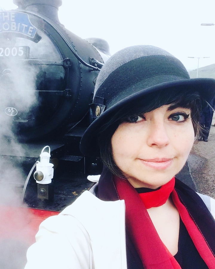 Personne prenant un selfie à côté d'un train à vapeur historique.