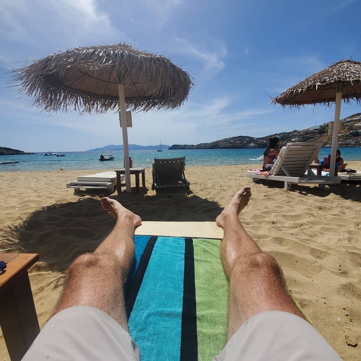 Personne se détendant sur une plage de sable avec des chaises longues donnant sur la mer.