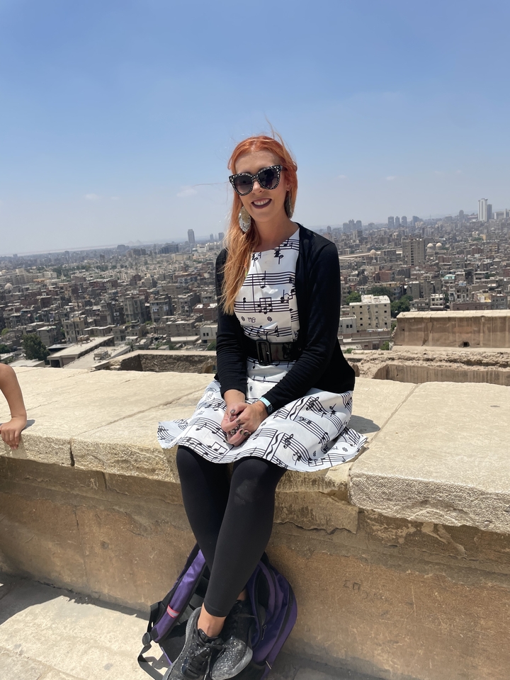 Personne assise sur un rebord avec un paysage urbain en arrière-plan.