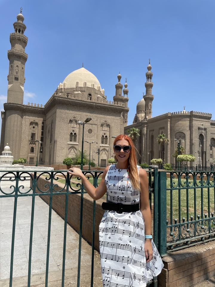 Personne debout devant une mosquée historique avec des minarets jumeaux.