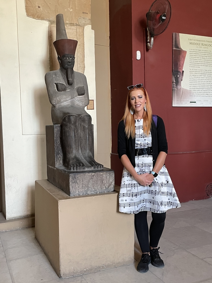 Personne à côté d'une statue de pierre assise à l'intérieur.