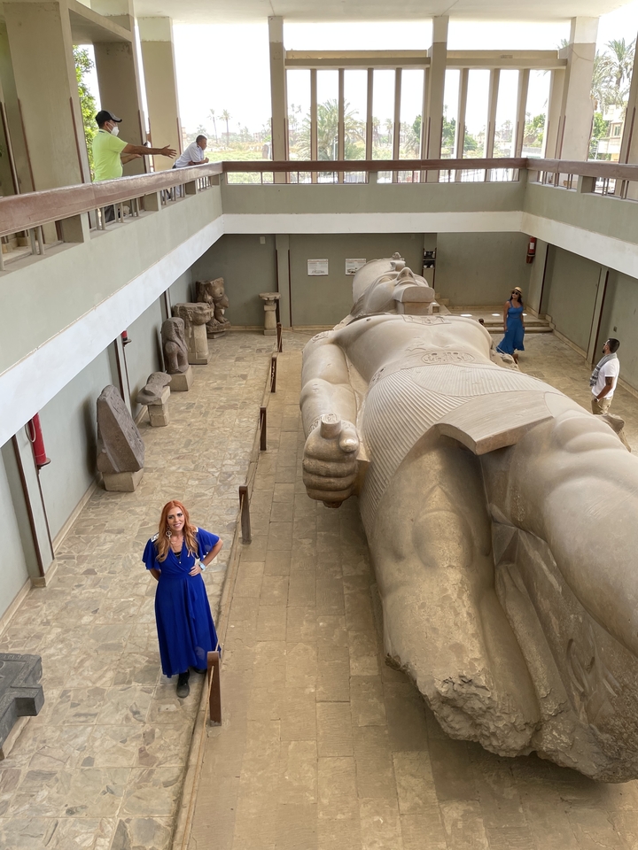 Personne debout à côté d'une grande statue de pierre à l'intérieur.