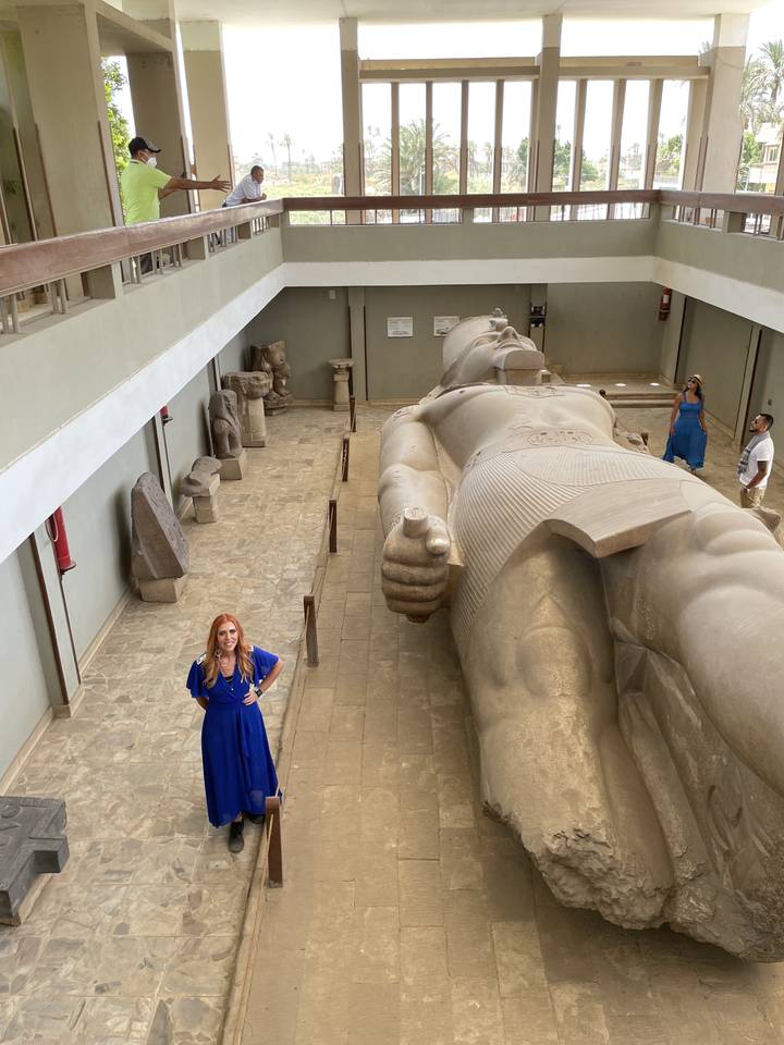 Personne debout à côté d'une grande statue allongée.