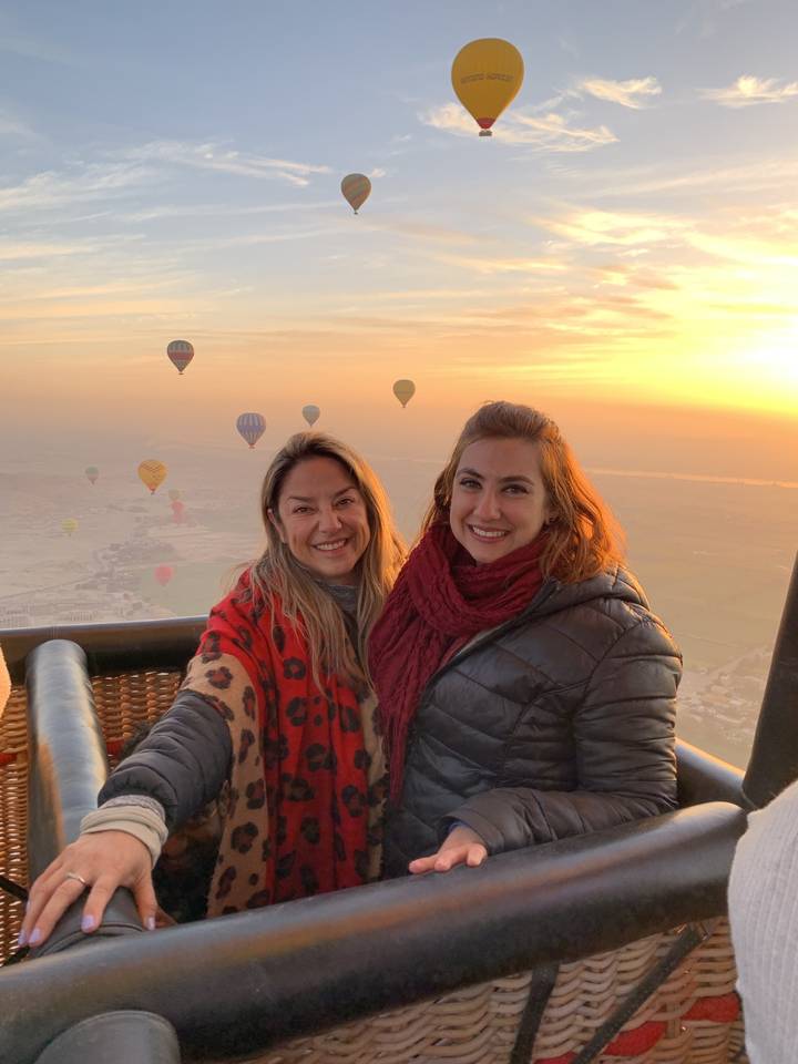 Deux femmes dans une montgolfière au lever du soleil.