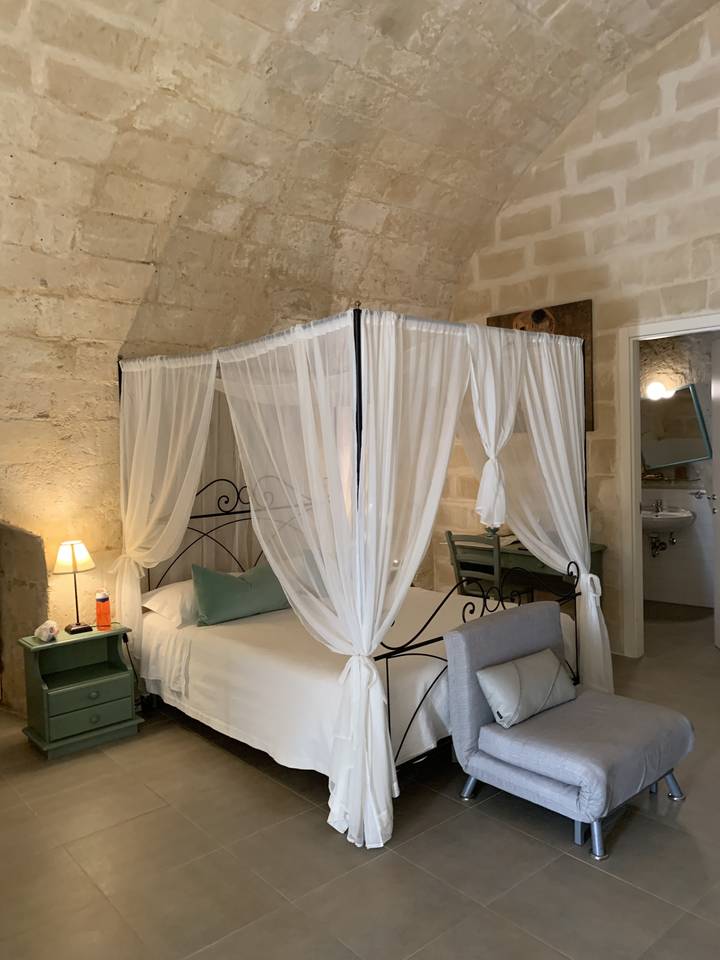 Intérieur d'une chambre en pierre avec un lit et un baldaquin décoratif.