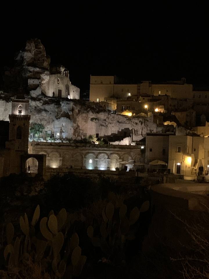 Bâtiments à flanc de falaise illuminés la nuit.