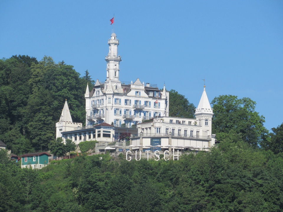 Bâtiment de style château sur une colline avec une grande enseigne Gutsch.
