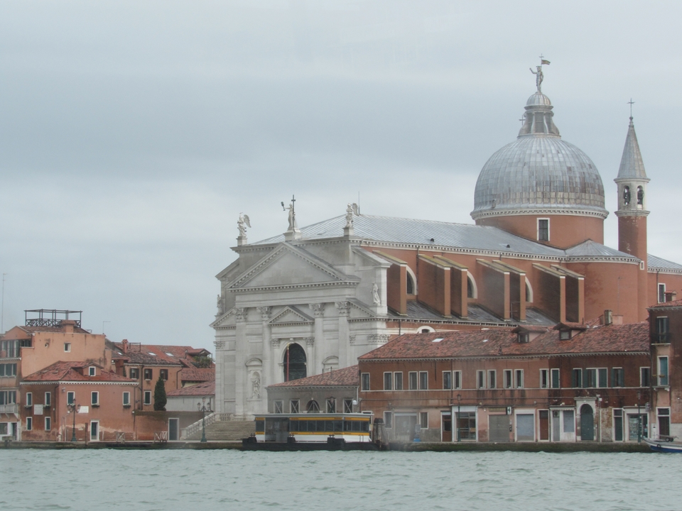 Grand bâtiment à coupole avec des statues sur un canal de Venise.