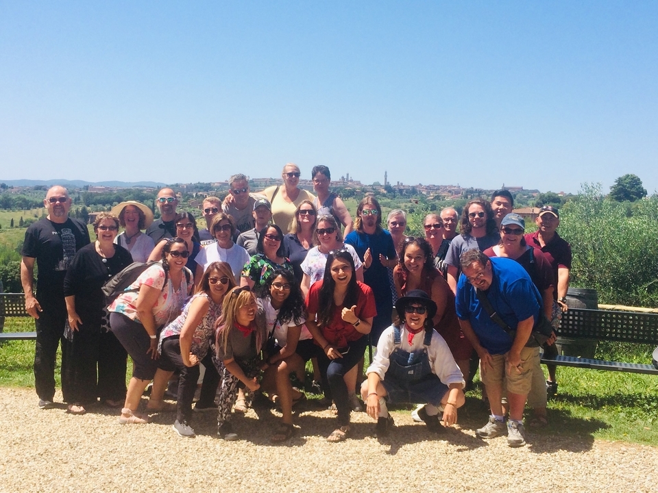 Un grand groupe de personnes posant ensemble à l'extérieur avec une ville en arrière-plan.