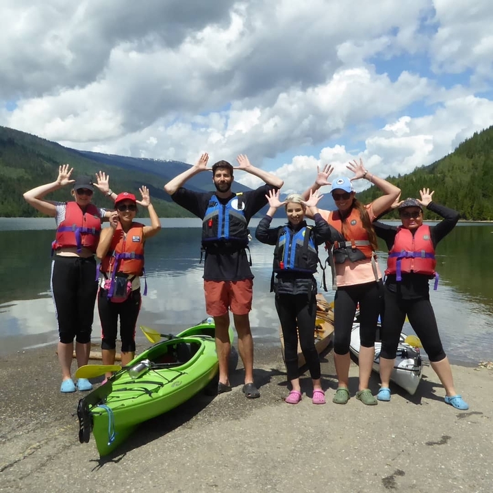 Group of people with kayaks by a lake.