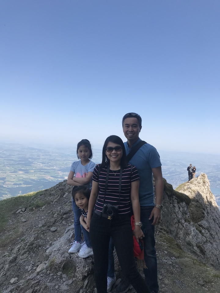 Famille posant sur une montagne avec des vues panoramiques.