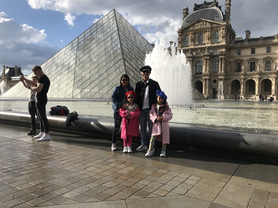 Famille posant devant la Pyramide du Louvre.