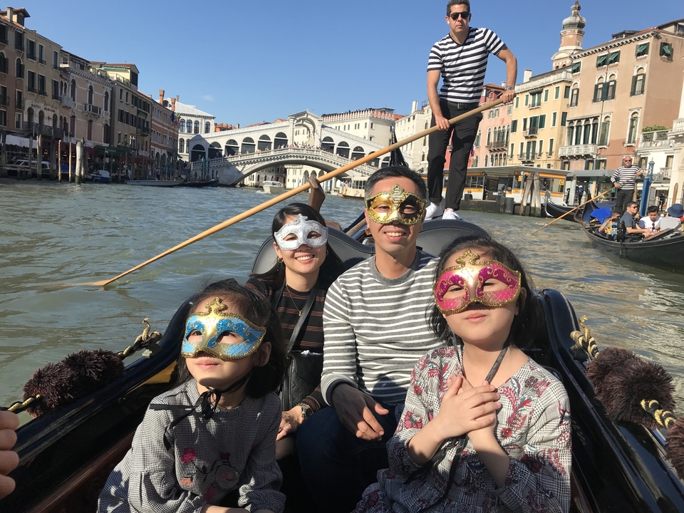 Famille portant des masques dans une gondole à Venise.