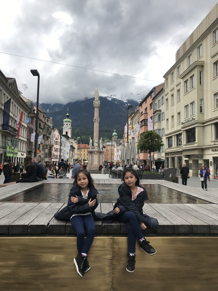 Des enfants assis devant une fontaine à Innsbruck.