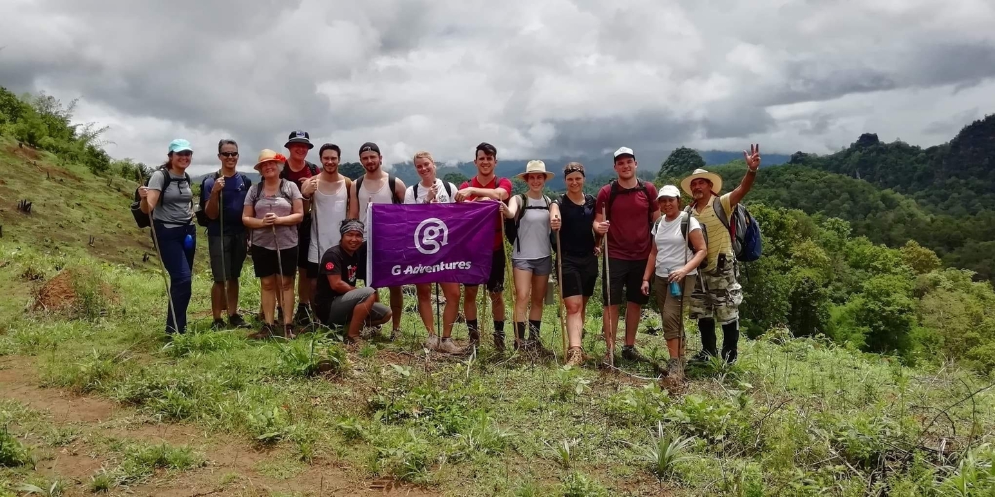 Un groupe de randonneurs posant avec un drapeau dans une région montagneuse.