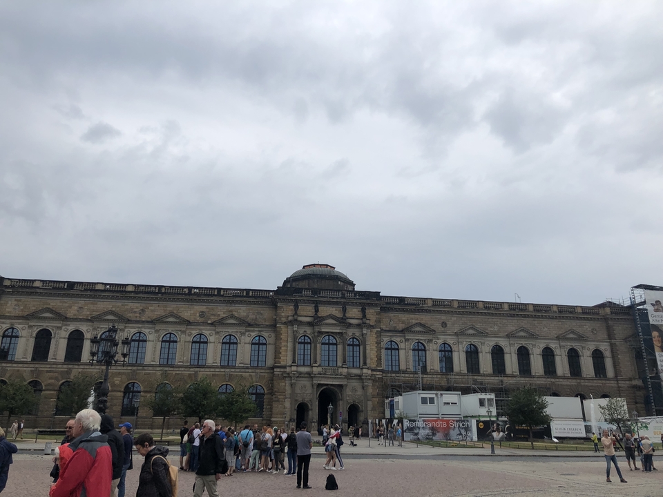 Bâtiment historique avec des statues sur la façade sous un ciel nuageux.
