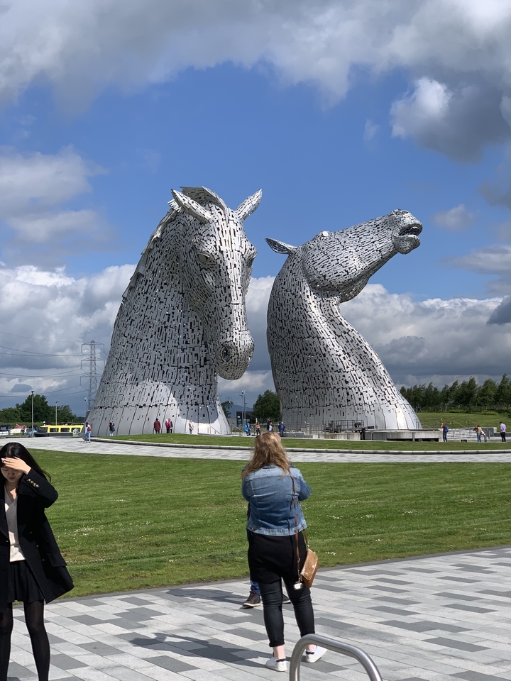 La sculpture des Kelpies avec des gens autour dans un parc verdoyant.