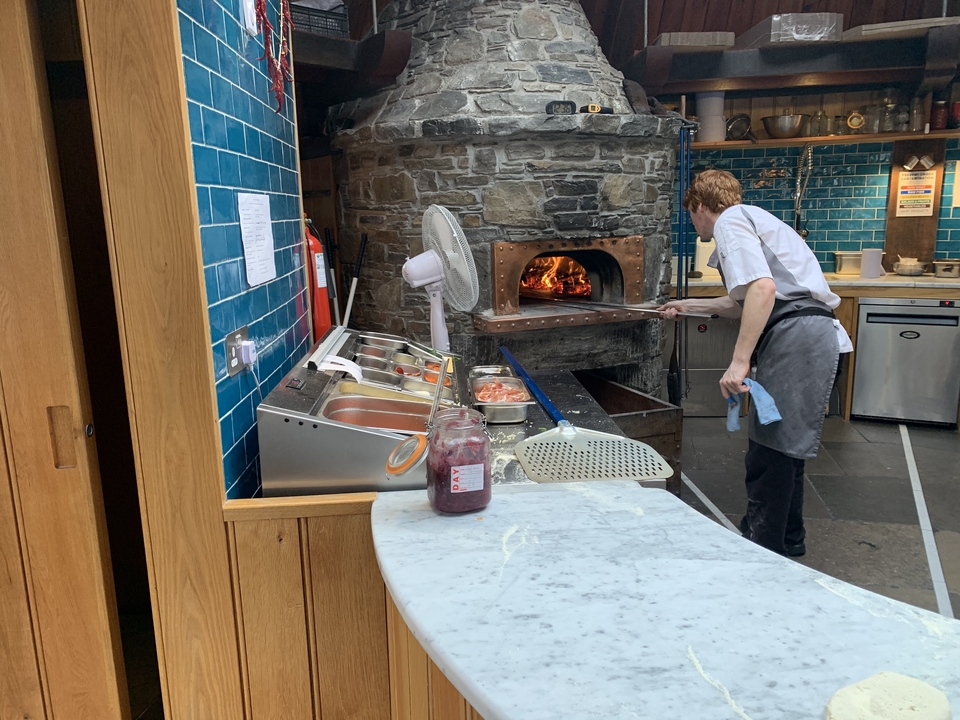 Chef cuisinant dans un four à pizza au feu de bois dans un restaurant.