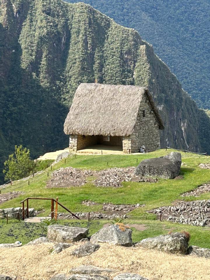 Steinhaus mit Strohdach am Bergrand.