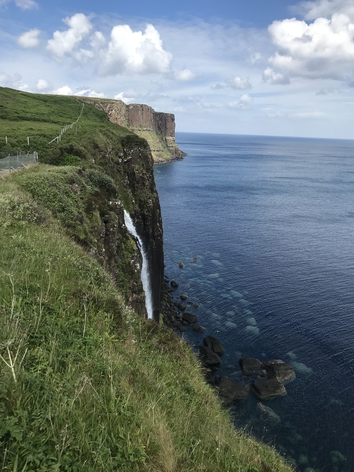 Dramatic waterfall cascading down a cliff into the ocean.